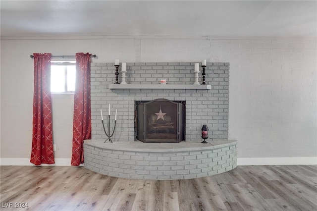 room details featuring a brick fireplace, ornamental molding, and wood-type flooring