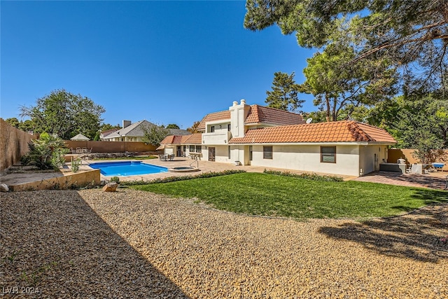 back of house featuring a yard, a fenced in pool, and a patio area