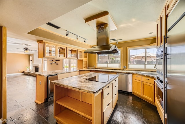 kitchen featuring light stone counters, kitchen peninsula, island range hood, stainless steel appliances, and a center island