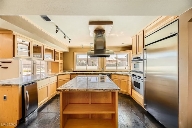 kitchen featuring appliances with stainless steel finishes, kitchen peninsula, a center island, light brown cabinetry, and sink