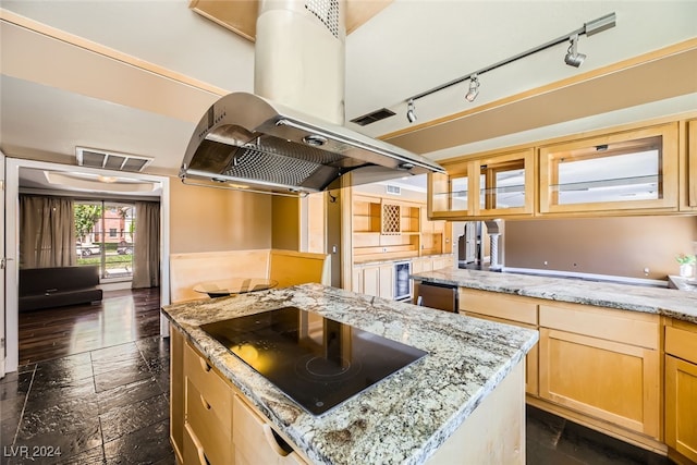 kitchen featuring black electric stovetop, light stone counters, a kitchen island, and rail lighting