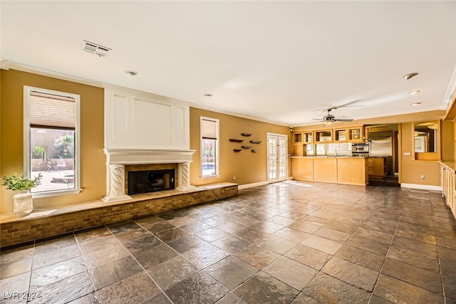 unfurnished living room with crown molding, ceiling fan, and a premium fireplace