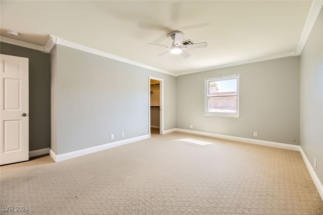 unfurnished bedroom with ornamental molding, a spacious closet, ceiling fan, and light colored carpet