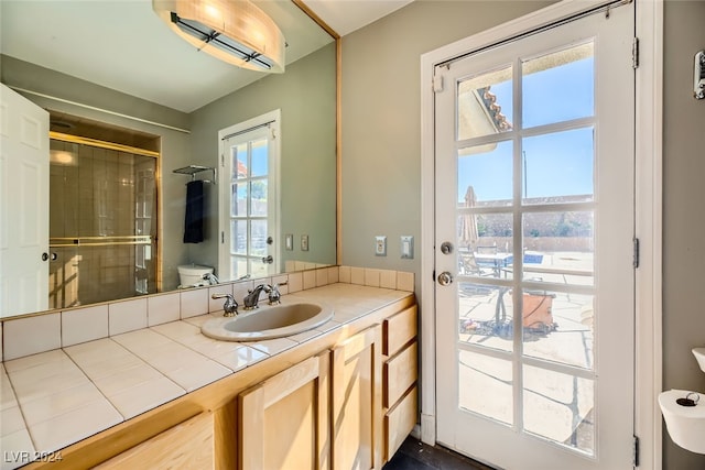 bathroom with walk in shower, vanity, toilet, and a healthy amount of sunlight