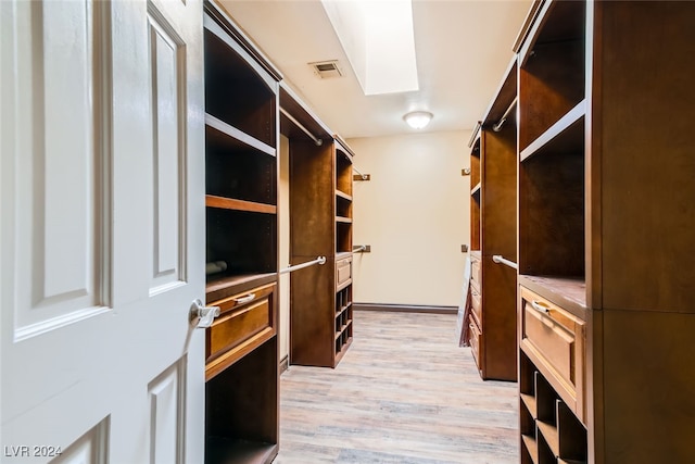 spacious closet featuring a skylight and light hardwood / wood-style flooring