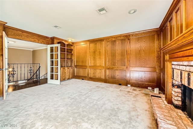 carpeted spare room with a brick fireplace, crown molding, and wooden walls