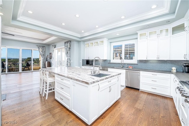 kitchen with a raised ceiling, white cabinetry, an island with sink, and appliances with stainless steel finishes