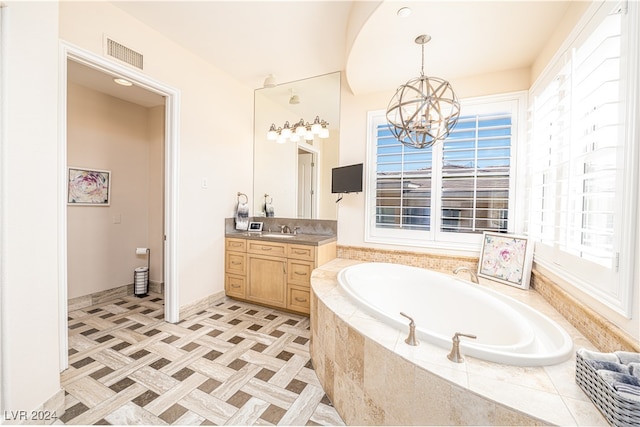 bathroom featuring vanity, tiled bath, and a notable chandelier