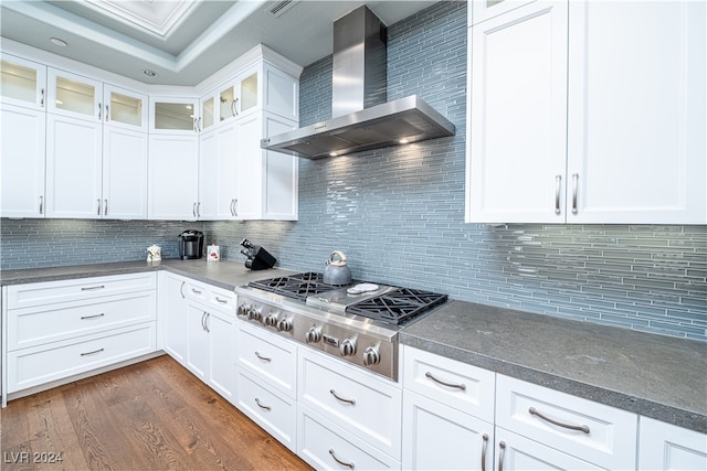 kitchen with white cabinets, decorative backsplash, wall chimney exhaust hood, and dark wood-type flooring