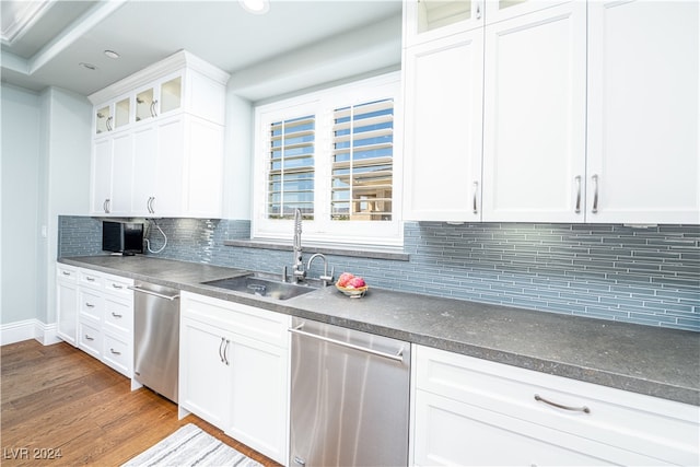 kitchen with white cabinetry, sink, tasteful backsplash, stainless steel dishwasher, and hardwood / wood-style flooring