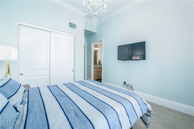 carpeted bedroom featuring a notable chandelier, ensuite bath, crown molding, and a closet