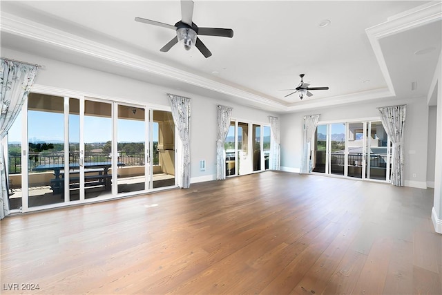 unfurnished living room featuring wood-type flooring, a raised ceiling, and ceiling fan