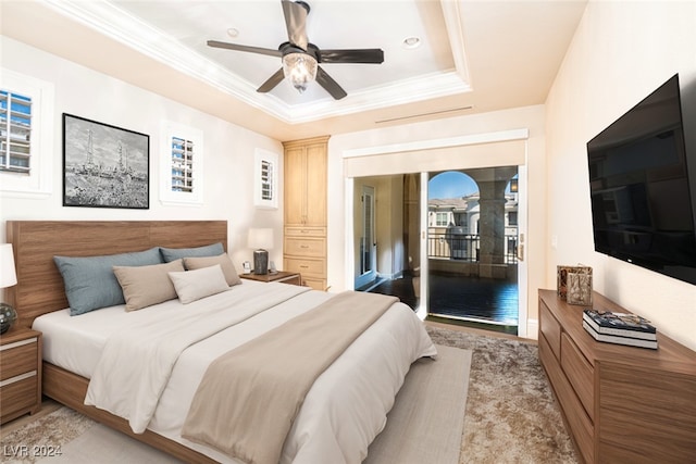 bedroom with ornamental molding, access to outside, a tray ceiling, ceiling fan, and light hardwood / wood-style flooring