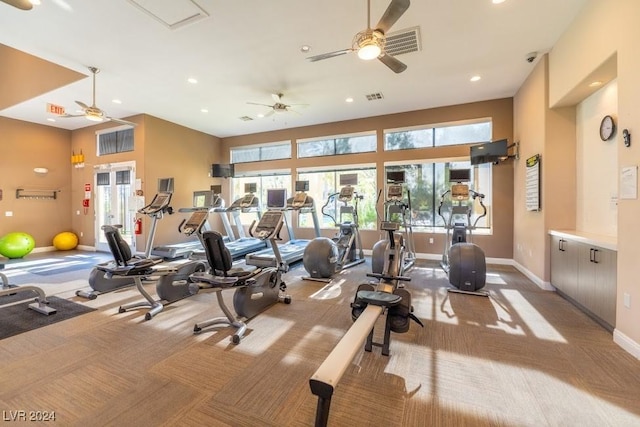 exercise room featuring a towering ceiling, light colored carpet, and ceiling fan