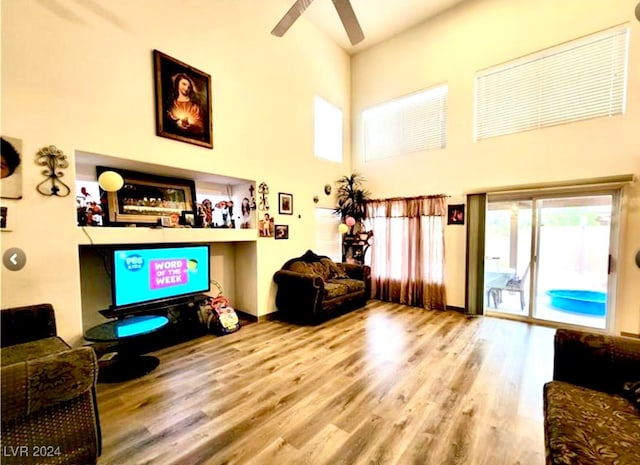 living room with a towering ceiling, ceiling fan, and hardwood / wood-style flooring