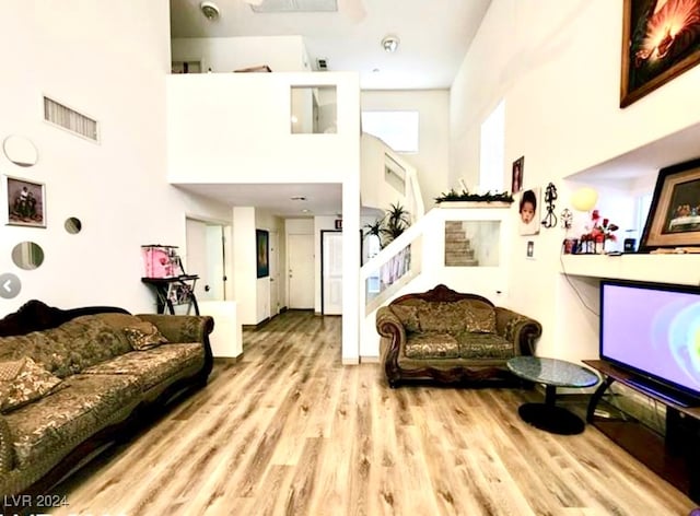 living room featuring a high ceiling, light hardwood / wood-style floors, and plenty of natural light