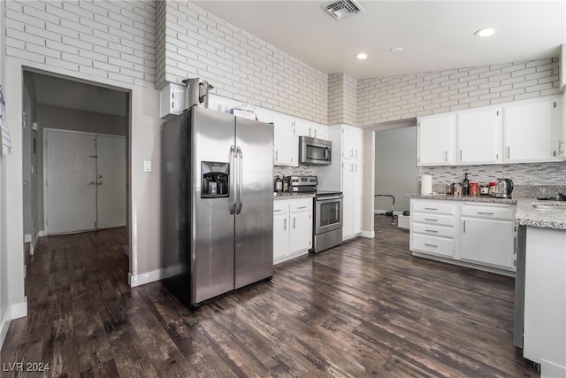 kitchen with lofted ceiling, dark wood-type flooring, appliances with stainless steel finishes, and white cabinets