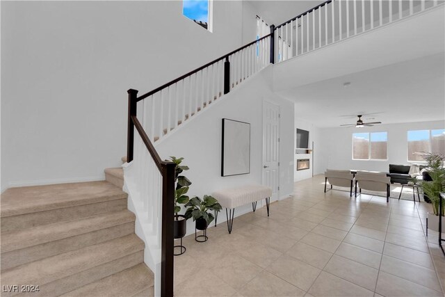 stairs with tile patterned flooring, a high ceiling, and ceiling fan