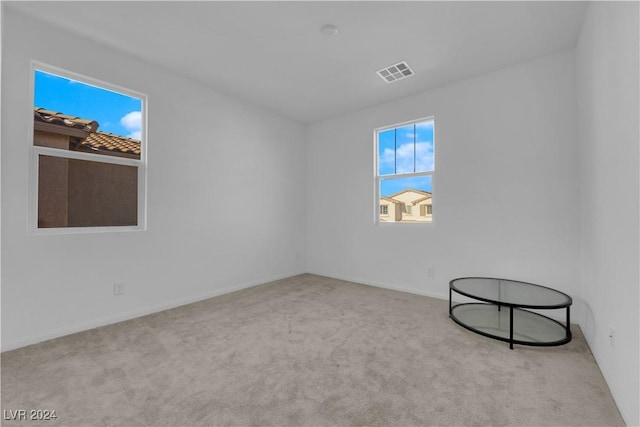 spare room featuring light carpet and visible vents