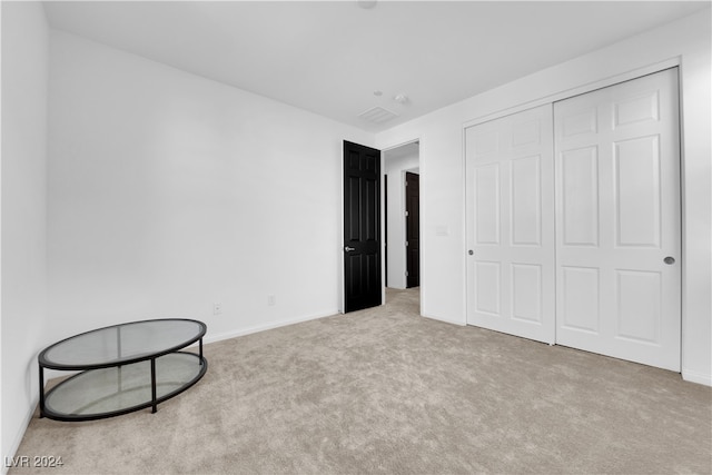 unfurnished bedroom with light carpet and a closet