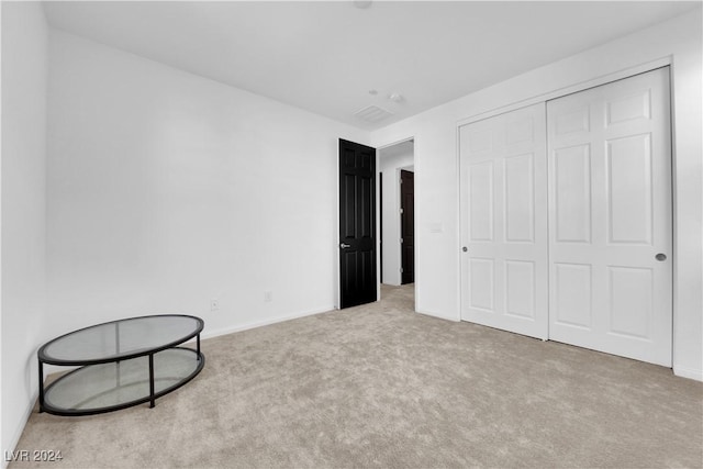 unfurnished bedroom with light carpet, a closet, and baseboards