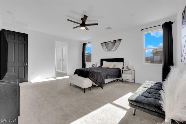 bedroom featuring a ceiling fan, visible vents, and light colored carpet