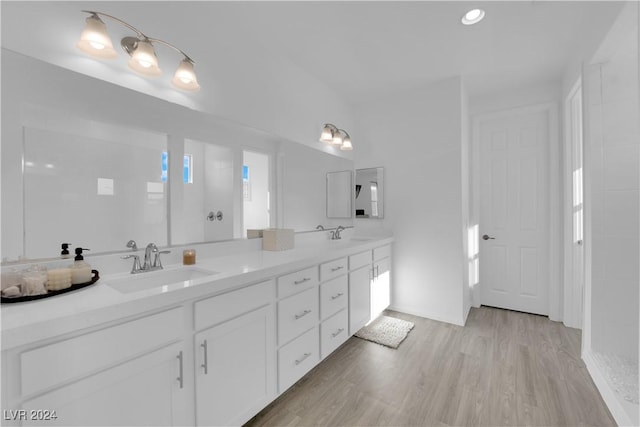 full bath with double vanity, wood finished floors, and a sink