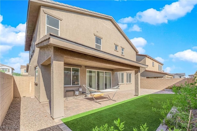 rear view of property featuring a fenced backyard, a patio, and stucco siding