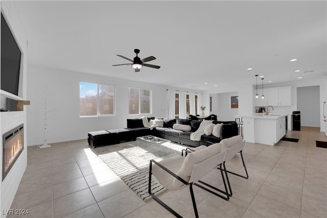 living room featuring ceiling fan, light tile patterned floors, and sink