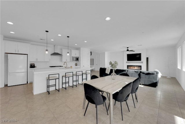 dining area with a ceiling fan, a glass covered fireplace, light tile patterned flooring, and recessed lighting