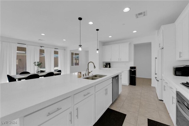 kitchen with white cabinets, light tile patterned flooring, pendant lighting, sink, and stainless steel appliances