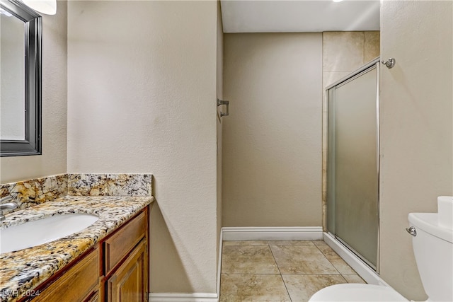 bathroom featuring tile patterned flooring, a shower with door, vanity, and toilet