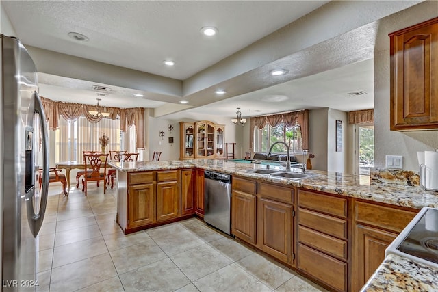 kitchen with sink, kitchen peninsula, an inviting chandelier, appliances with stainless steel finishes, and decorative light fixtures