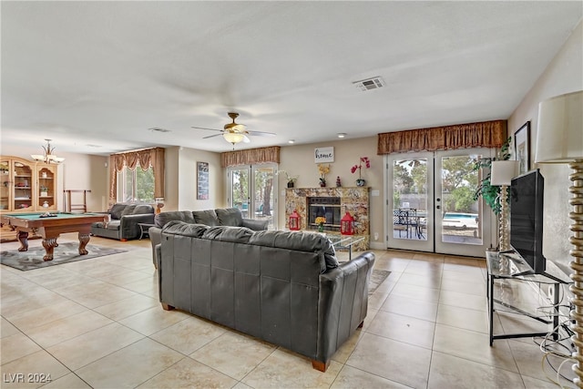 tiled living room featuring french doors, ceiling fan, billiards, and a stone fireplace