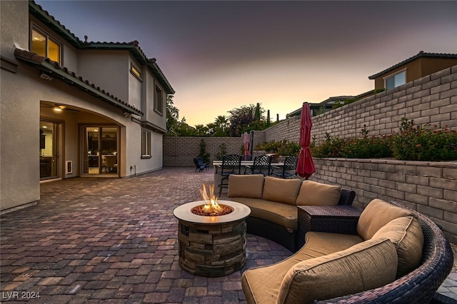 patio terrace at dusk with an outdoor living space with a fire pit