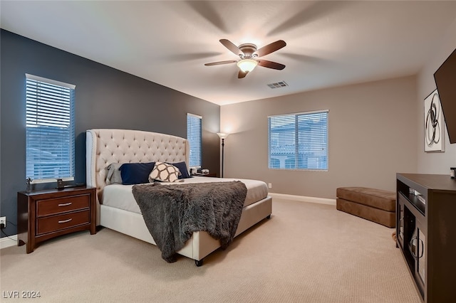 bedroom featuring multiple windows, light carpet, and ceiling fan