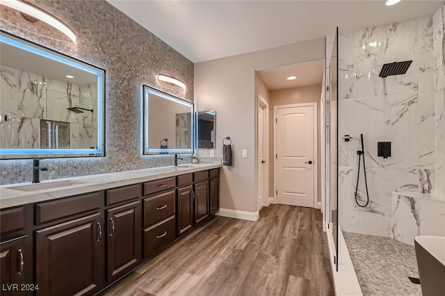 bathroom with wood-type flooring, vanity, and a tile shower