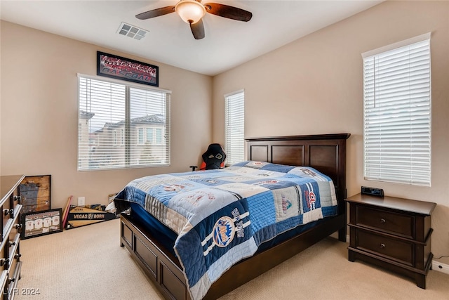 bedroom featuring ceiling fan, light colored carpet, and multiple windows