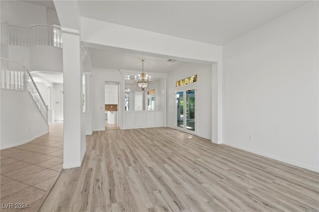 unfurnished living room with an inviting chandelier and light hardwood / wood-style flooring