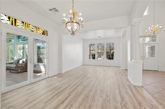 interior space featuring light wood-type flooring, an inviting chandelier, and ornate columns