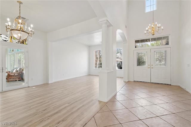 foyer featuring a notable chandelier, light hardwood / wood-style floors, decorative columns, and a healthy amount of sunlight