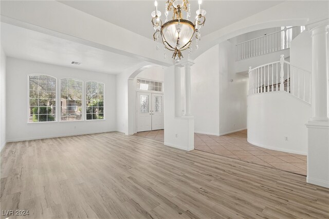 interior space with a notable chandelier, decorative columns, and light hardwood / wood-style floors