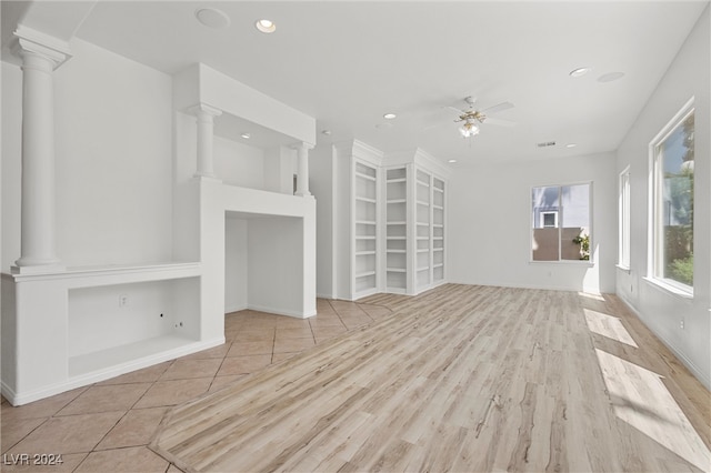 unfurnished living room featuring light wood-type flooring, ceiling fan, and decorative columns