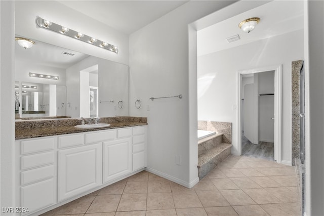 bathroom with a tub to relax in, vanity, and tile patterned floors