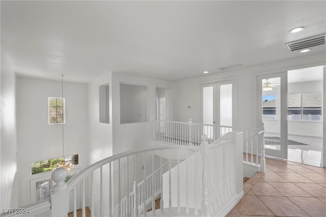 hall featuring light tile patterned flooring and an inviting chandelier