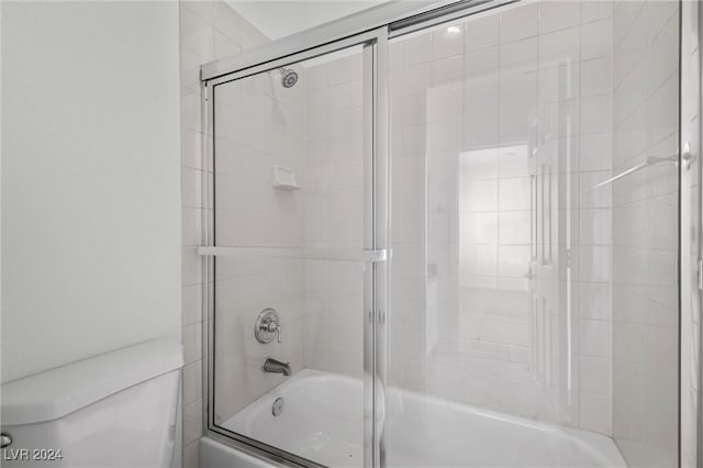 bathroom featuring enclosed tub / shower combo and toilet