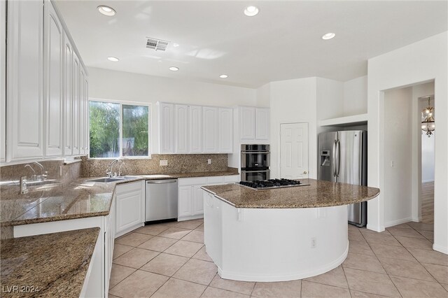 kitchen with white cabinets, a kitchen island, stainless steel appliances, backsplash, and stone countertops