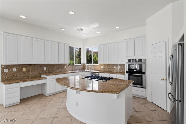 kitchen featuring stainless steel appliances, white cabinetry, a kitchen island, and stone counters