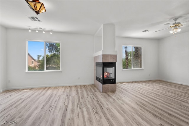 unfurnished living room with light wood-type flooring, ceiling fan, and a tile fireplace