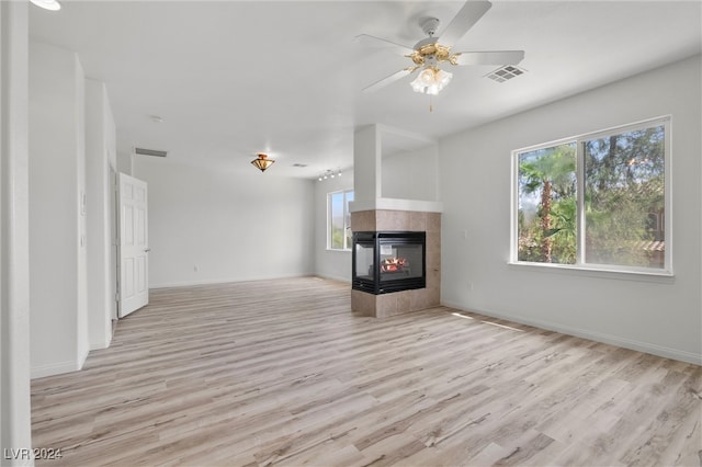 unfurnished living room featuring light hardwood / wood-style floors, ceiling fan, and a tile fireplace